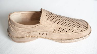 Erkek bej rengi deri ayakkabılar, model mokasenler. Işık arkaplanda yakın plan çekimleri.