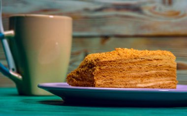 Yeşil ahşap arka planda bir parça kek ve bir fincan kahve..