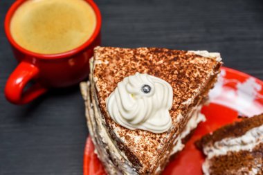 Kremalı ekşi pasta ve kırmızı bardakta taze kahve.