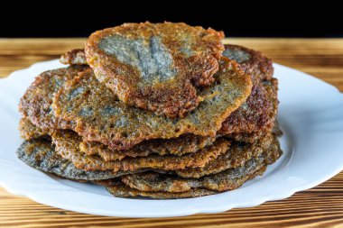 Tahta bir taşrada, beyaz bir tabakta bir yığın patatesli krep.