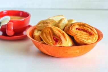 Reçelli puf böreği ve beyaz ahşap arka planda kahve kupası.