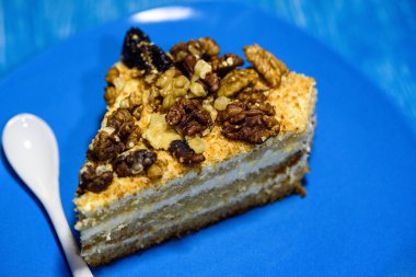 Cevizli kek dilimi, ahşap arka planda, turkuaz bir plakaya yakın plan çekilmiş..