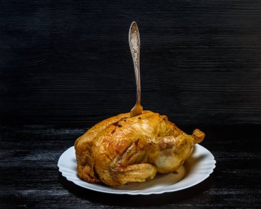 Beyaz tabakta kızarmış tavuk, siyah ahşap arka planda.