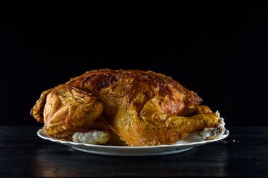 Kızarmış tavuk, ahşap bir arka planda beyaz bir tabakta.