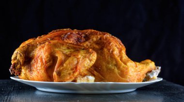 Kızarmış tavuk, ahşap bir arka planda beyaz bir tabakta.