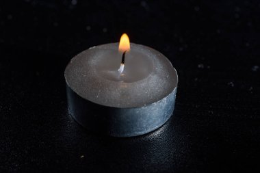 Karanlık bir arka planda sönen bir mumun ateşi.