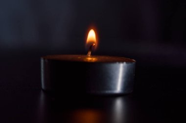 Karanlık bir arka planda sönen bir mumun ateşi.