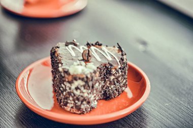 Kırmızı tabakta kalp şeklinde bir dilim çikolatalı pasta..