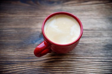 Eski ahşap arka planda kırmızı bardakta kahve.