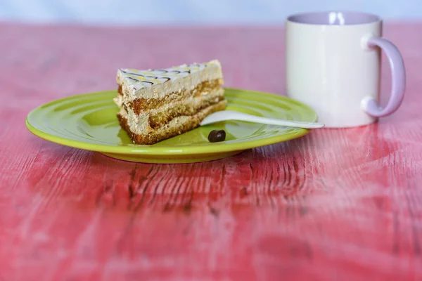 A piece of sponge cake on a plate on a wooden table.