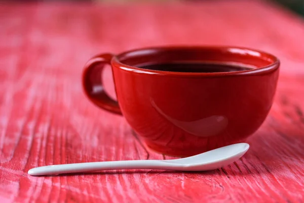 A cup of coffee on a red wooden background.