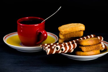 Koyu arkaplanda kahve fincanında waffle ruloları.