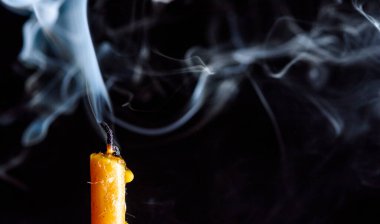 Karanlık bir arka planda sönen bir mumu tüttürmek.