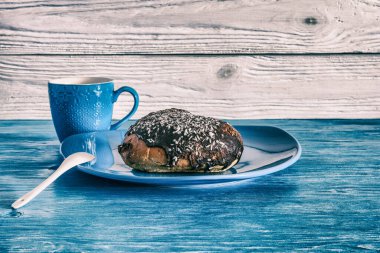 Tahta arka planda turkuaz plakalı bir çörek. Fotoğraflı yakın plan..