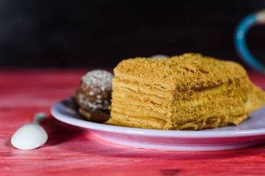 Katmanlı sünger keki, çikolatalı tatlılar ve tahta arka planda bir fincan kahve..