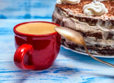 Kremalı ekşi pasta ve kırmızı bardakta taze kahve.