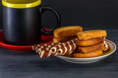 Koyu arkaplanda kahve fincanında waffle ruloları.