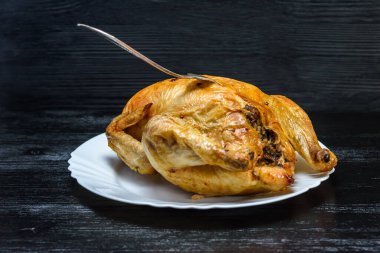 Beyaz tabakta kızarmış tavuk, siyah ahşap arka planda.