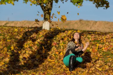 Düşen yaprakların üzerinde oturan kız.