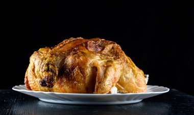 Kızarmış tavuk, ahşap bir arka planda beyaz bir tabakta.