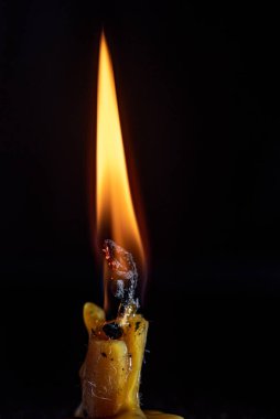 Yanan bir mumun alevi karanlık bir arka plana karşı.