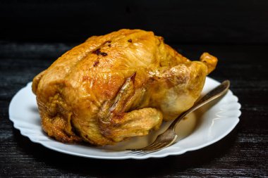 Beyaz tabakta kızarmış tavuk, siyah ahşap arka planda.