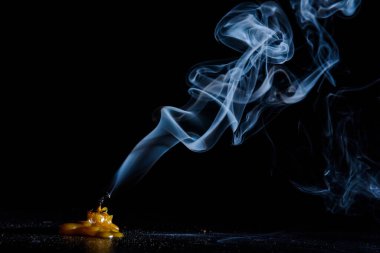 Karanlık bir arka planda sönen bir mumu tüttürmek.