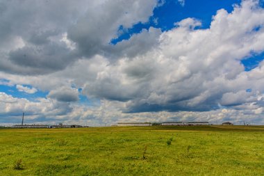 Mavi gökyüzünün arka planında yeşil alan üzerinde beyaz bulutlar