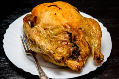 Beyaz tabakta kızarmış tavuk, siyah ahşap arka planda.