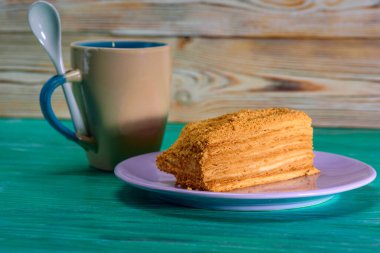 Yeşil ahşap arka planda bir parça kek ve bir fincan kahve..
