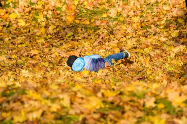 Çocuk düşen yapraklarla oynuyor.