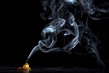 Karanlık bir arka planda sönen bir mumu tüttürmek.