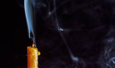 Karanlık bir arka planda sönen bir mumu tüttürmek.