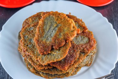 Tahta bir taşrada, beyaz bir tabakta bir yığın patatesli krep.