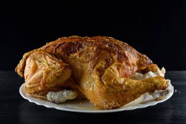 Kızarmış tavuk, ahşap bir arka planda beyaz bir tabakta.