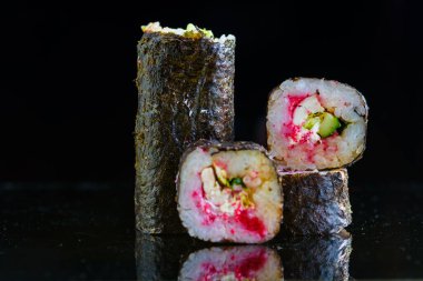 Suşi siyah ayna arka planında yuvarlanıyor..