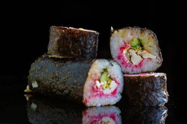 Suşi siyah ayna arka planında yuvarlanıyor..