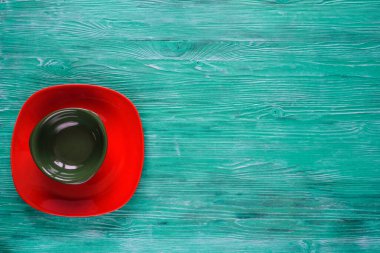 Yeşil ahşap zemin üzerinde boş kırmızı tabak.