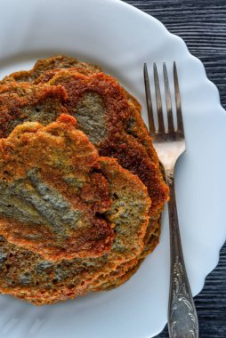 Tahta bir taşrada, beyaz bir tabakta bir yığın patatesli krep.