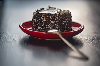 Kırmızı tabakta kalp şeklinde bir dilim çikolatalı pasta..