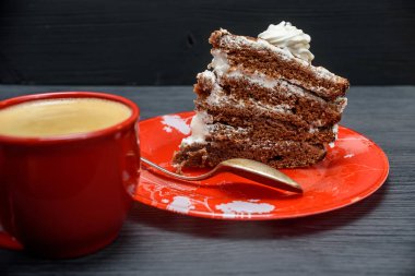 Kremalı ekşi pasta ve kırmızı bardakta taze kahve.