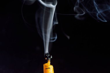 Karanlık bir arka planda sönen bir mumu tüttürmek.