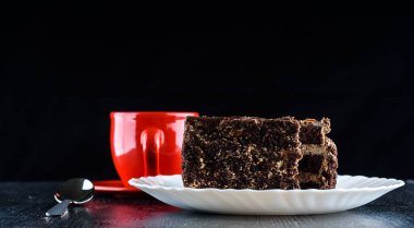 Bir tabak çikolatalı kek, bir fincan kahvenin yanında.