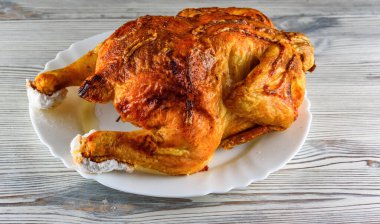 Kızarmış tavuk, ahşap bir arka planda beyaz bir tabakta.