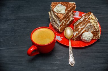 Kremalı ekşi pasta ve kırmızı bardakta taze kahve.