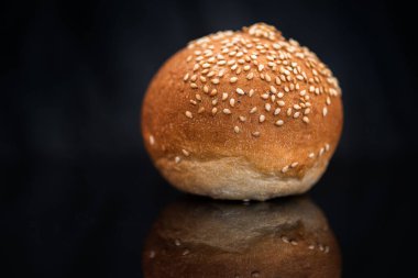 Siyah arkaplanda susam tohumlu çörek.