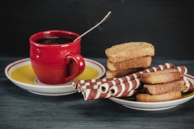 Koyu arkaplanda kahve fincanında waffle ruloları.