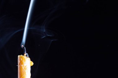 Yanan bir mumun alevi karanlık bir arka plana karşı.