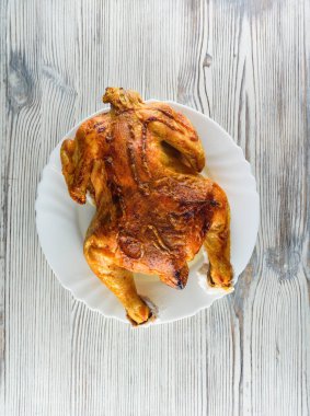 Kızarmış tavuk, ahşap bir arka planda beyaz bir tabakta.