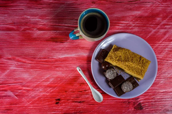 Katmanlı sünger keki, çikolatalı tatlılar ve tahta arka planda bir fincan kahve..